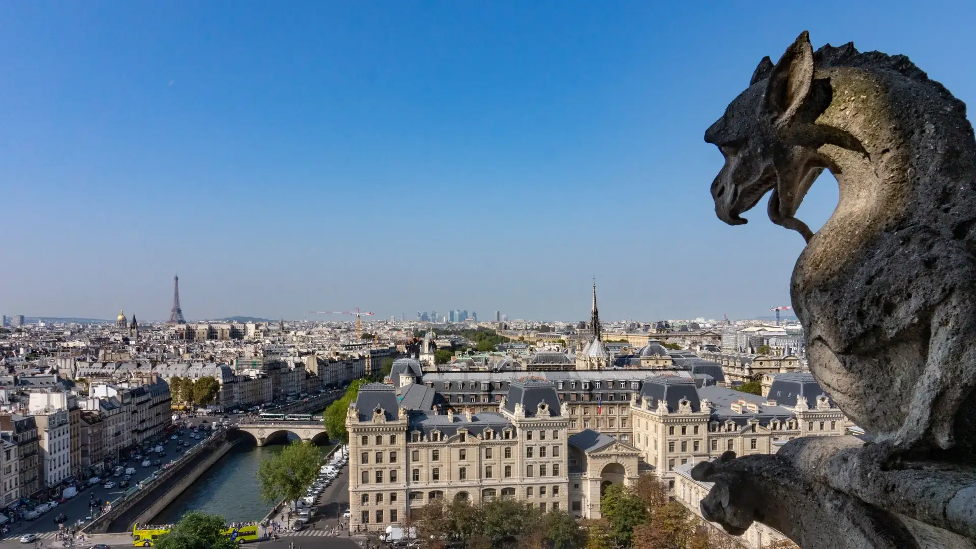 A stone chimera on Notre-Dame's gallery looking out over the Seine, the Île de la Cité and the Eiffel Tower on the skyline